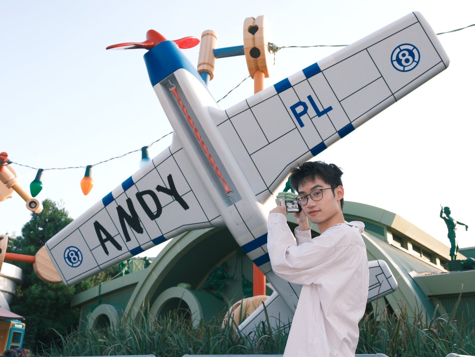 Andy 的生活照：明亮天空下，红蓝白飞机装置前举起相机拍照